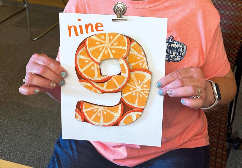 person holding a drawing of the number 9